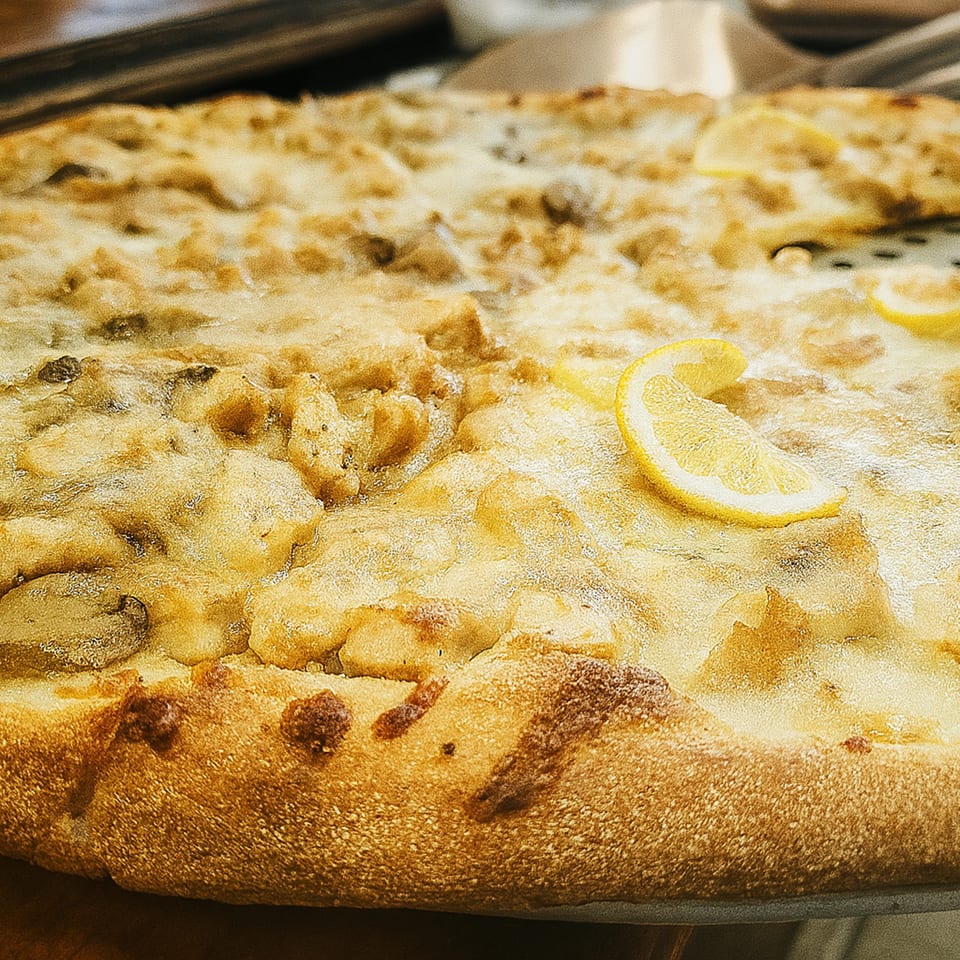 Cibo's white pizza with chicken, mushrooms, and lemon slices on a metal tray.