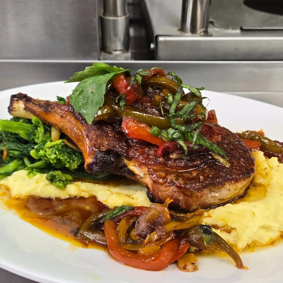 Cibo's pork chop with peppers, broccolini, mashed potatoes, and a rich sauce.