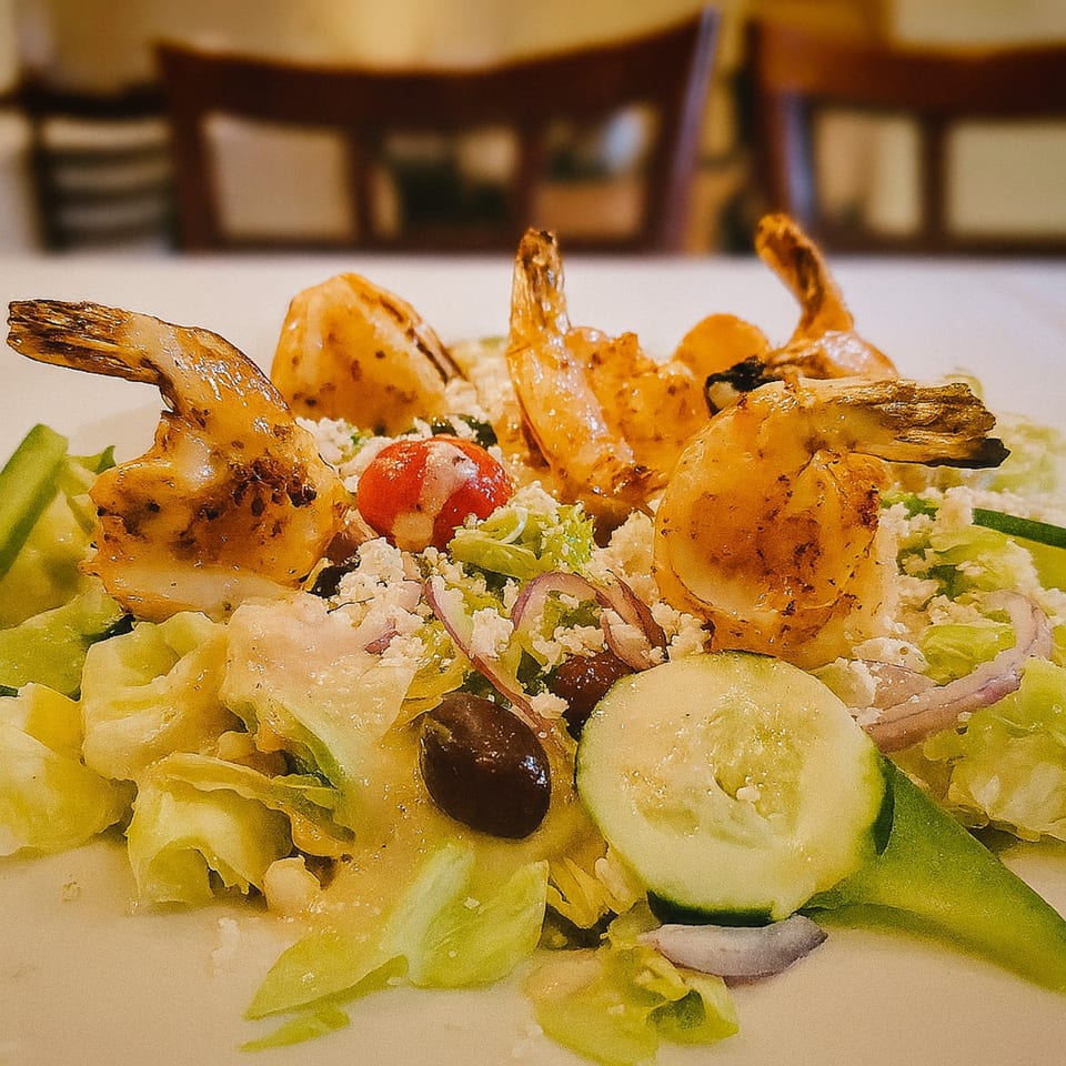 Grilled shrimp salad with lettuce, cucumbers, tomatoes, olives, red onion, and feta cheese.