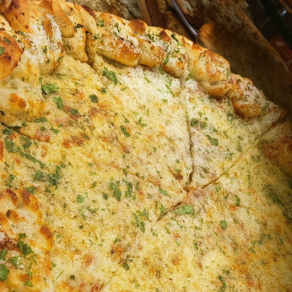 Close-up of a Cibo garlic pizza with a thick crust, sprinkled with cheese and parsley.